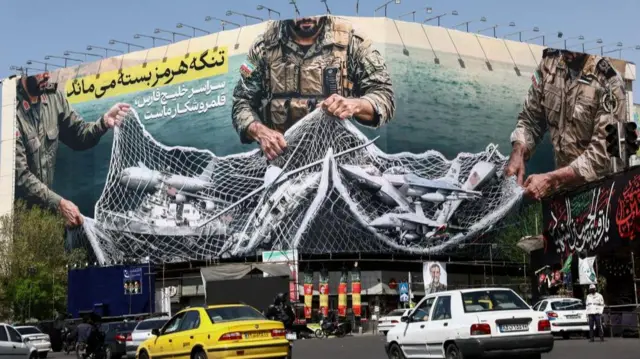 A billboard in Tehran - apparently showing the Iranian military collecting US ships and aircraft in a net - seen in Tehran on Sunday