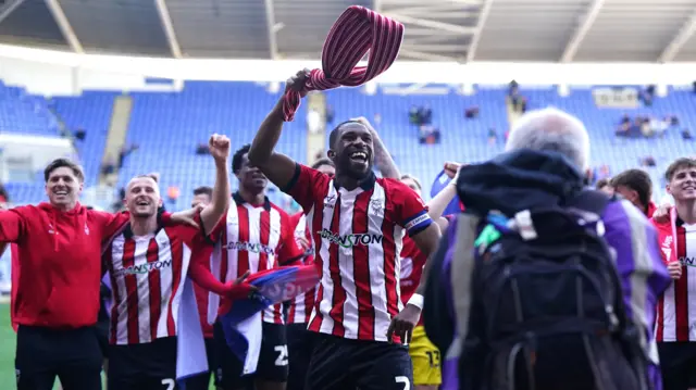Lincoln captain Tendayi Darikwa waves a scarf over his head in celebration