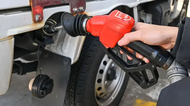 A driver refuels a vehicle at a petrol station