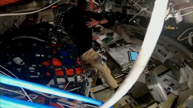 Two astronauts can be seen hugging each other inside the spacecraft with two more behind them