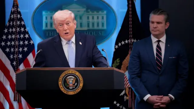 Donald Trump speaks at the White House with Pete Hegseth behind him