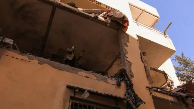 A man talks on the phone while inspecting damage at the site of an Israeli strike on an apartment building in Ain Saadeh, Lebanon, on Monday morning