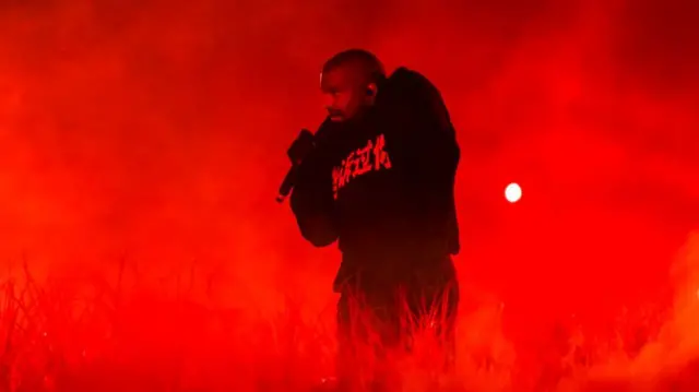 Kanye West performing, bathed in red light