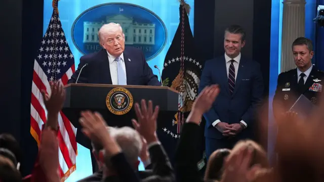 Trump looking at a room of reporters from a podium