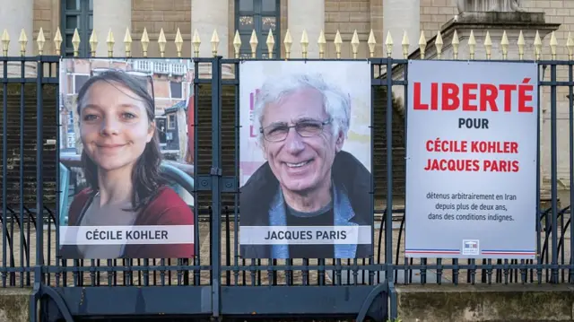 Portrait placards of Cecile Kohler and Jacques Paris, two French citizens formerly detained in Iran, set up on a fence of the French National Assembly, in Paris on March 11, 2026