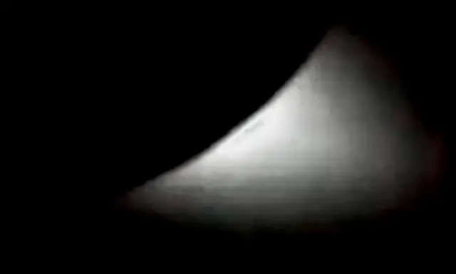 A black and white low-resolution image shows a solar eclipse as seen by the Artemis II astronauts