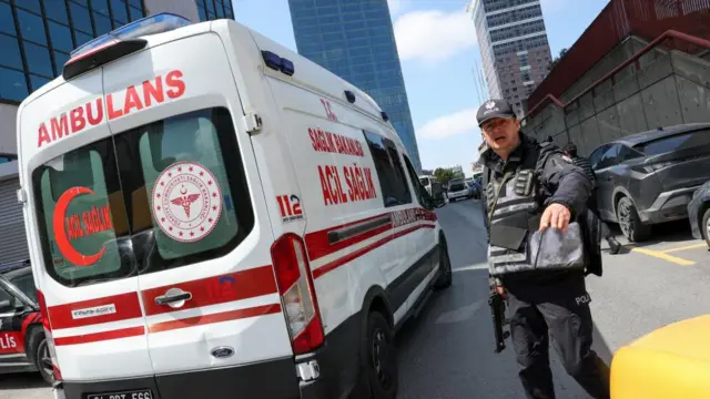 An armed police officer stands next to an ambulance close to the scene of the shooting
