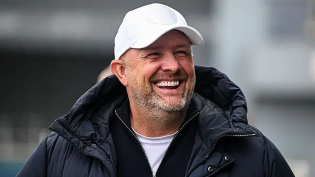 A smiling Bromley boss Andy Woodman wearing a white baseball cap
