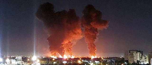 Four large smoke plumes and fires visible from a distance