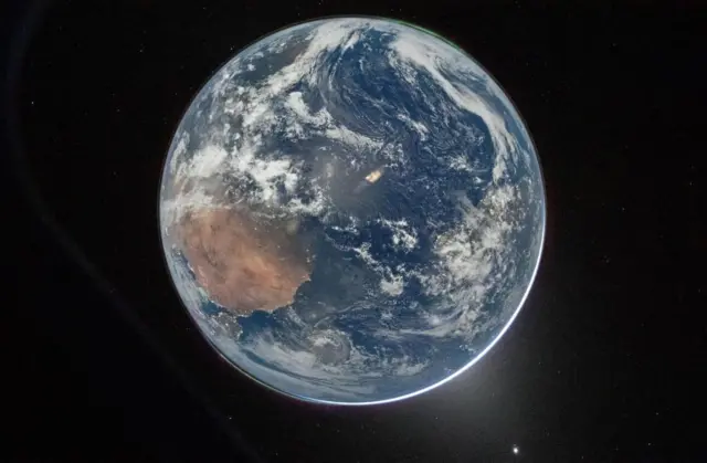 A view of Earth taken by NASA astronaut and Artemis II Commander Reid Wiseman from one of the Orion spacecraft’s window after completing the translunar injection burn on 2 April, 2026/ The planet is seen against a dark space backdrop with the light from the sun visible in the bottom right corner