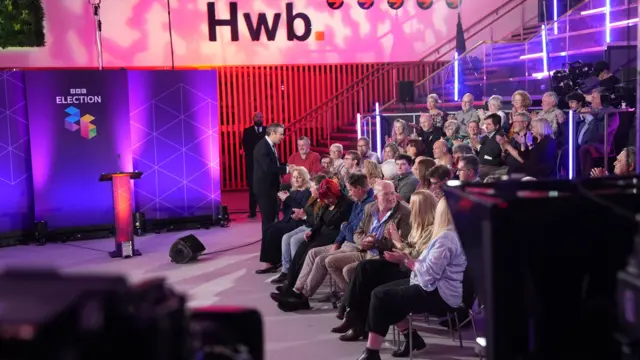 Wide image showing audience clapping at event.