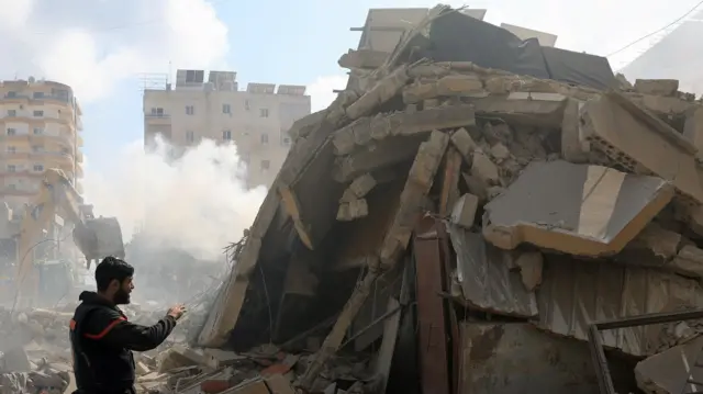A rescuer stands next to a pile of rubble at the site of an Israeli strike in Tyre, Lebanon, April 8, 2026.