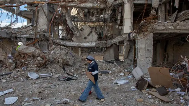 A woman walks among buildings destroyed in a joint attack by Israel and the United States on April 6, 2026, in Tehran, Iran