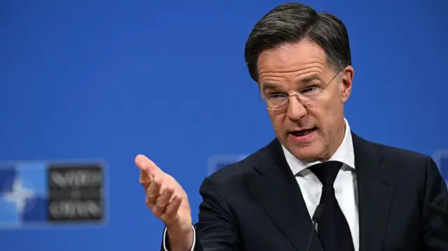 Rutte speaks while wearing a black jacket and tie