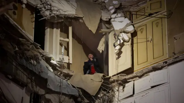 A woman waits to be rescued from a damaged building