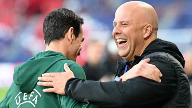 Arne Slot, Manager of Liverpool, interacts with an UEFA member of staff