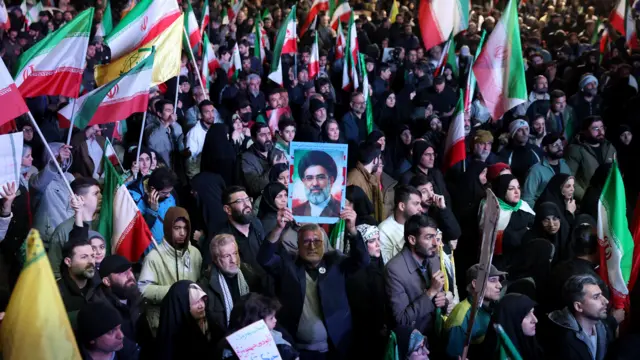 Iranians wave green and red flags during a demonstration following the announcement of a two-week ceasefire at Enghelab Square in Tehran.