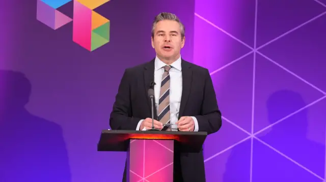 A man is wearing a suit while standing behind a podium, and in front of a purple background which says "BBC election"