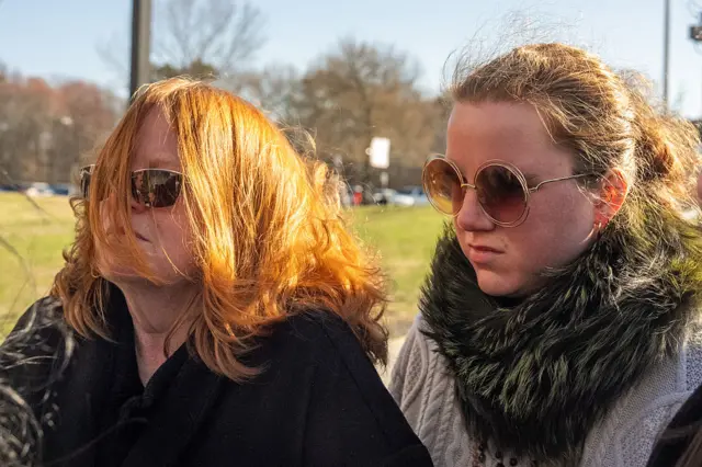 Two red-headed woman in sunglasses arrive at court on a sunny day