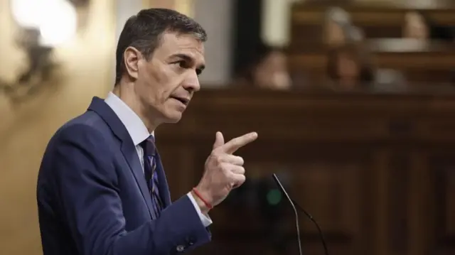 Pedro Sanchez speaking in a room panelled with wood