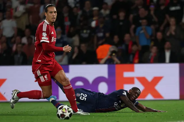 Paris Saint-Germain's Portuguese defender Nuno Mendes falls next to Liverpool's Dutch defender Virgil van Dijk (