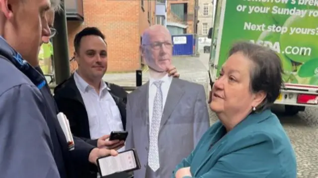 Scottish Labour's deputy leader Jackie Baillie stands outside SNP HQ with a cardboard cutout of John Swinney