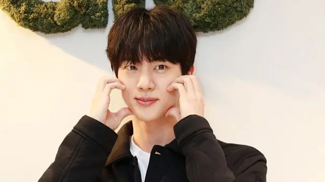 Jin making a heart gesture