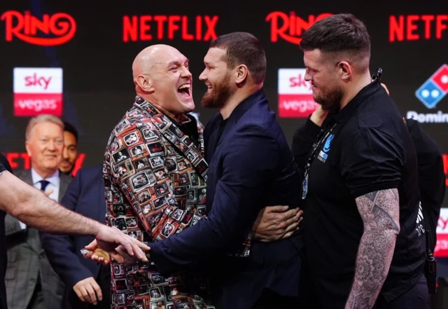 Tyson Fury laughs in a hug with Arslanbek Makhmudov
