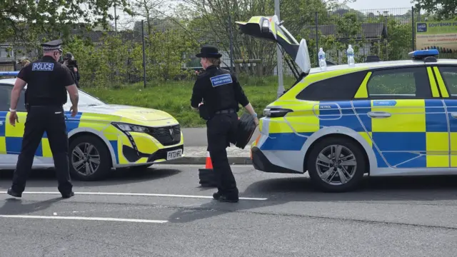 Police officers in front of police vehicles removing cones.