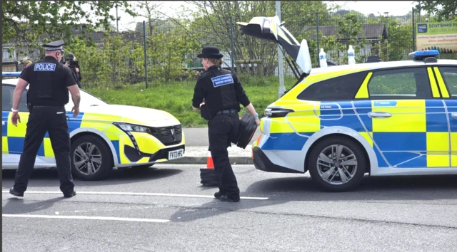 Two police officers in front of two police cars
