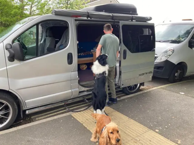 A man and two dogs beside a camper van