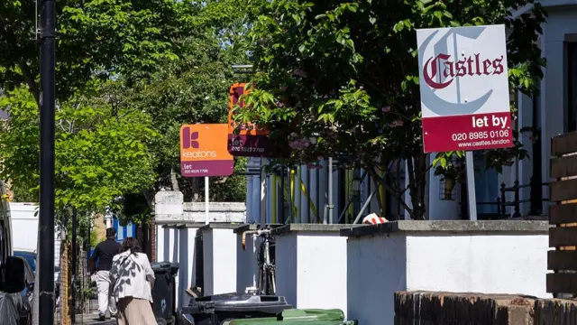 A row of houses with 'to let' signs posted outside