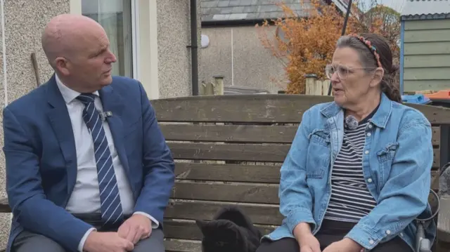 Glenn Campbell and Cathy Duff sitting on a bench having a conversation.