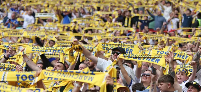 Leeds fans holding up yellow scarves at Wembley