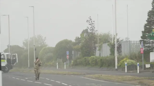A Army specialist walking from the smoke in the area.