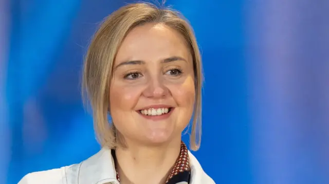 Mairi McAllan speaking on a stage with a blue background
