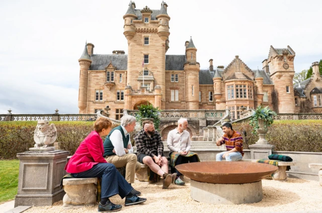 Celebrity Traitors 2025 cast sitting on stone benches outside the main location, a castle in Scotland