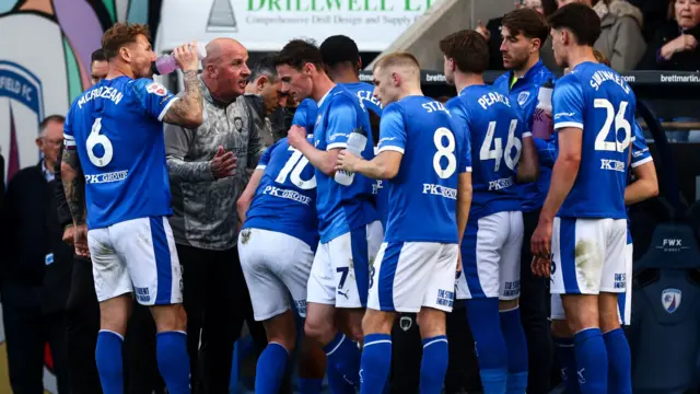 Paul Cook speaks to his Chesterfield players on the touchline