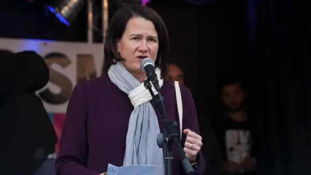 Hornsey and Friern Barnet MP Catherine West pictured speaking into a microphone, wearing a purple coat and lilac and white scarf