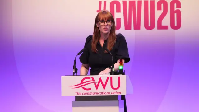 Angela Rayner in black dress delivering speech on stage, a white lectern in front of her with the logo of the CWU The communication union