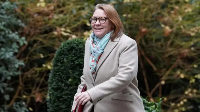 Anna Turley is pictured walking outdoors, wearing a long light-coloured coat and a patterned light green scarf.