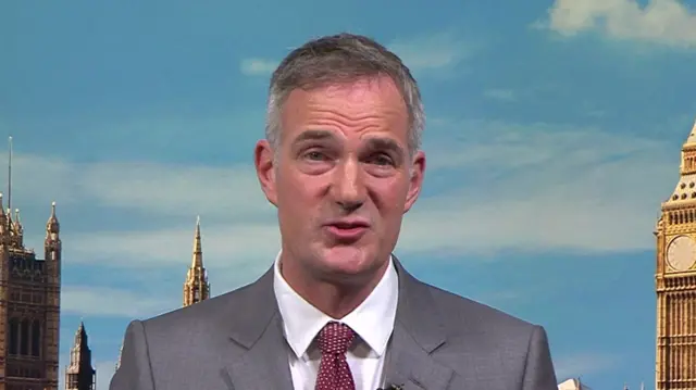 Peter Kyle in a grey suit appearing on BBC Breakfast. The Houses of Parliament and Big Ben appear on a backdop behind him.