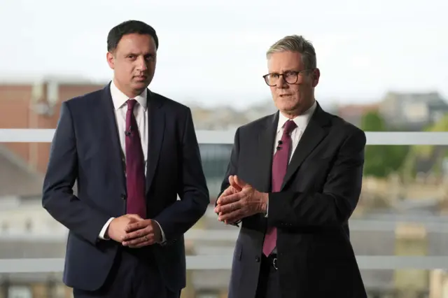 Prime Minister Sir Keir Starmer and Scottish Labour Leader Anas Sarwar standing next to one another. Both wear dark suits and maroon ties