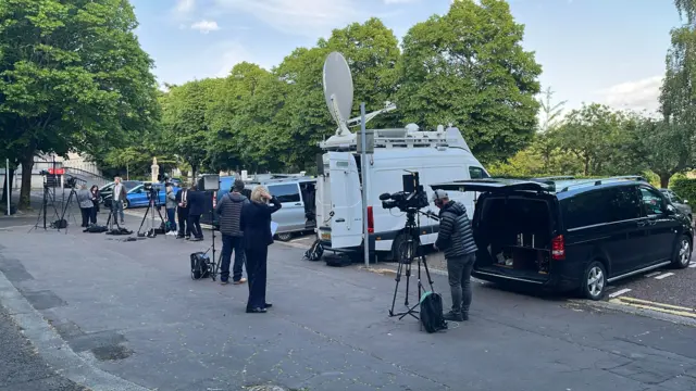 Media wait outside a building