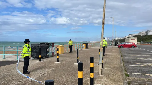 Three officers in hi-vis stand on the pavement
