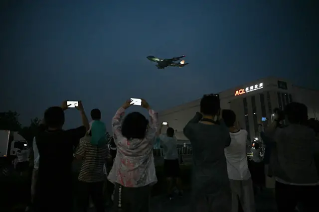 People gather to get a view of Air Force One, carrying US President Donald Trump, arriving at Beijing Capital Airport in Beijing on May 13, 2026.