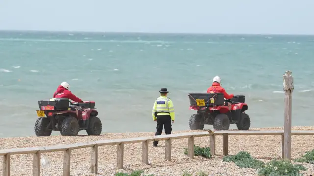 Quad bikes drive either side of a police officer on Brighton beach