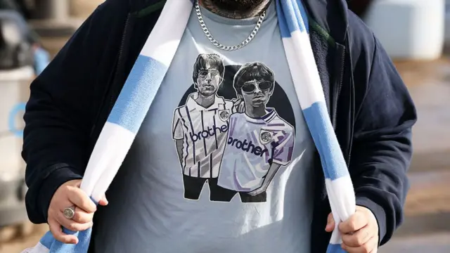 : A Manchester City fan poses for a photo wearing a shirt featuring Liam Gallagher and Noel Gallagher prior to the Premier League match between Manchester City and Crystal Palace