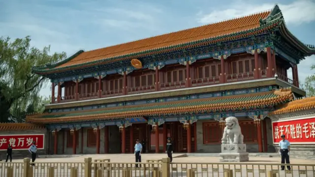 Security guards stand outside a traditional Chinese building with a curved roof