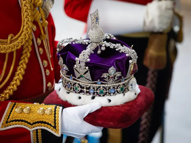 The Imperial State Crown being carried on a red velvet cushion